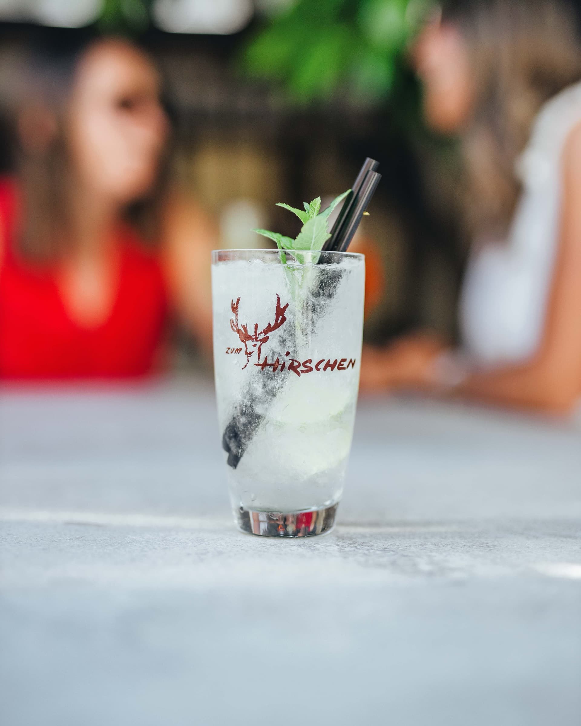 Drink im Glas mit dem Hirschen-Logo