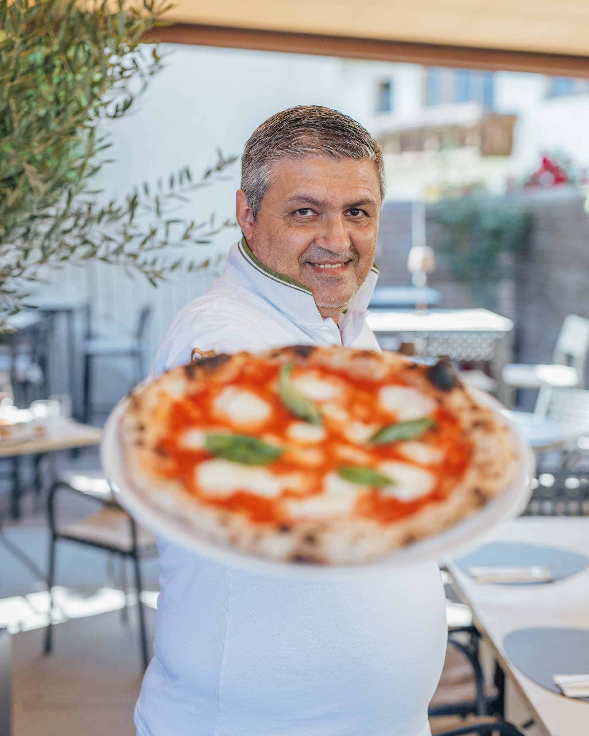 Pizzaiolo mit einer Pizza Margherita